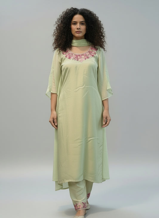 Woman wearing a light green outfit with pink KASHMIRI AARI WORK embroidery indoors.